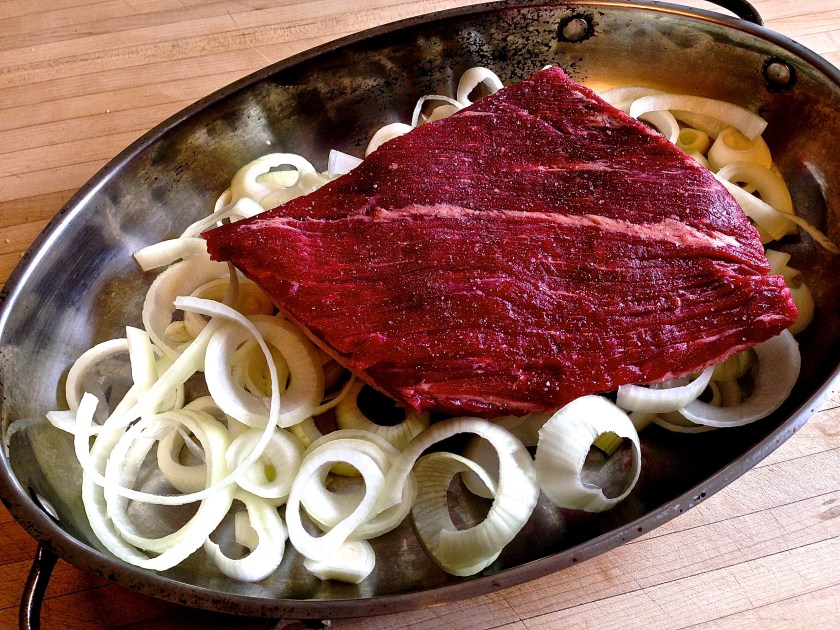 Lay the meat over a layer of thickly sliced rings of onion, and season well.